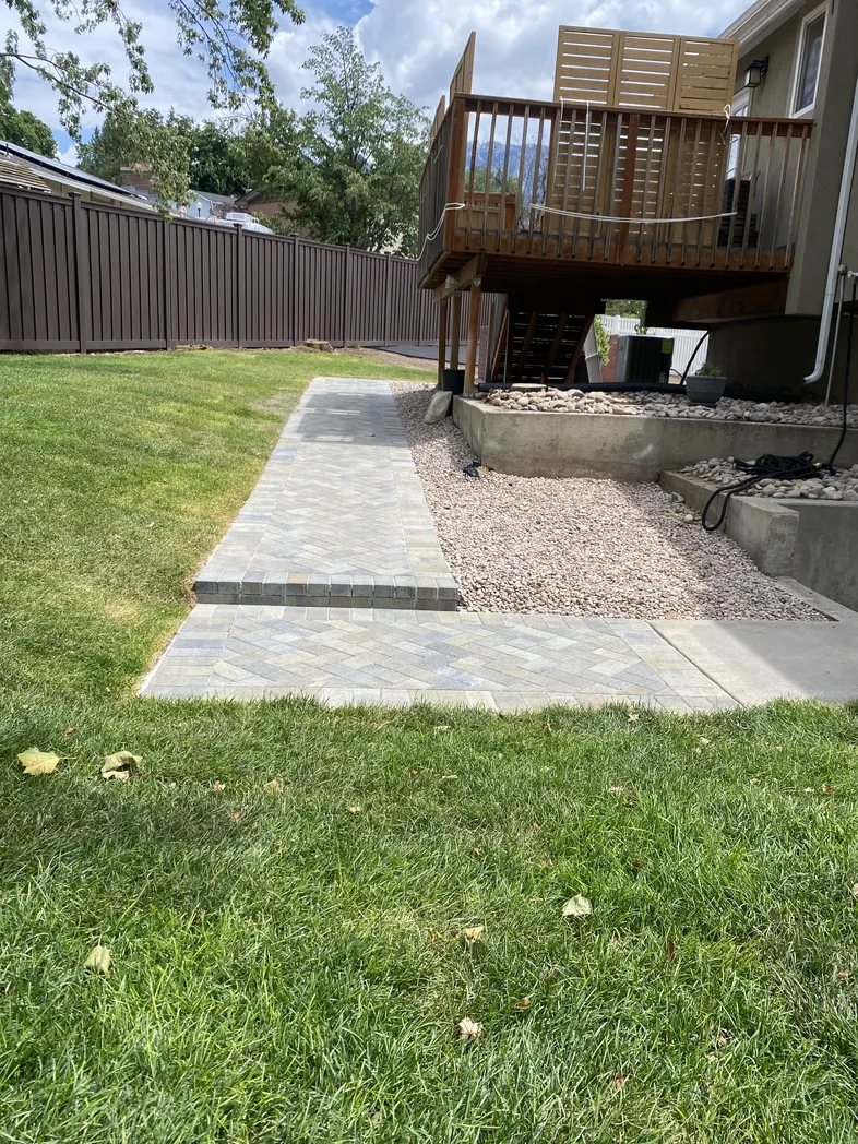 Basement entry hardscaping path and yard transition by Aloha Pavers & Concrete